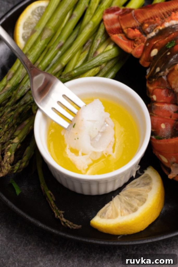 Crispy Air-Fried Lobster Tails 8 A fork dipping a piece of lobster meat into melted butter. A glistening, perfectly cooked piece of air-fried lobster meat being dipped into a small, inviting bowl of melted butter, highlighting its succulent texture and rich flavor.