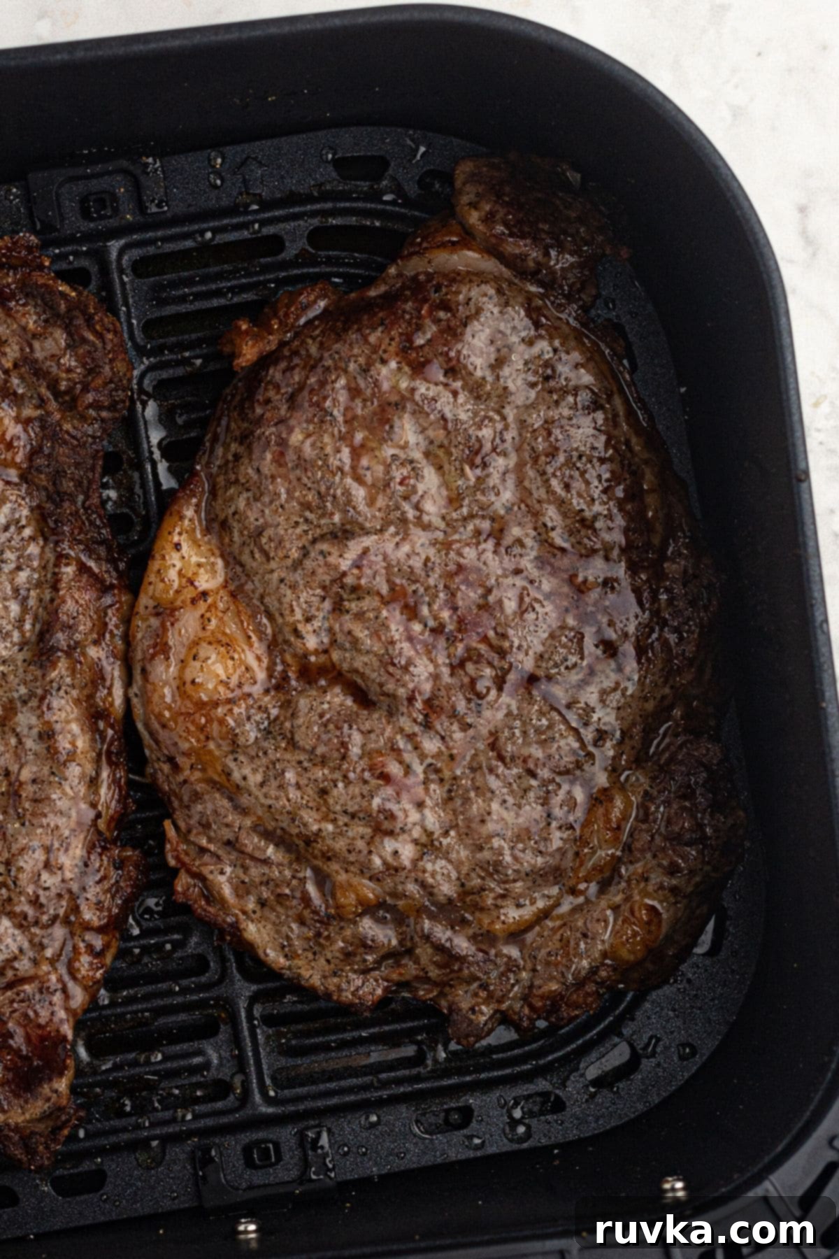 Ultimate Air Fryer Ribeye 6 Juicy, seasoned ribeye steak in the air fryer basket after being cooked.