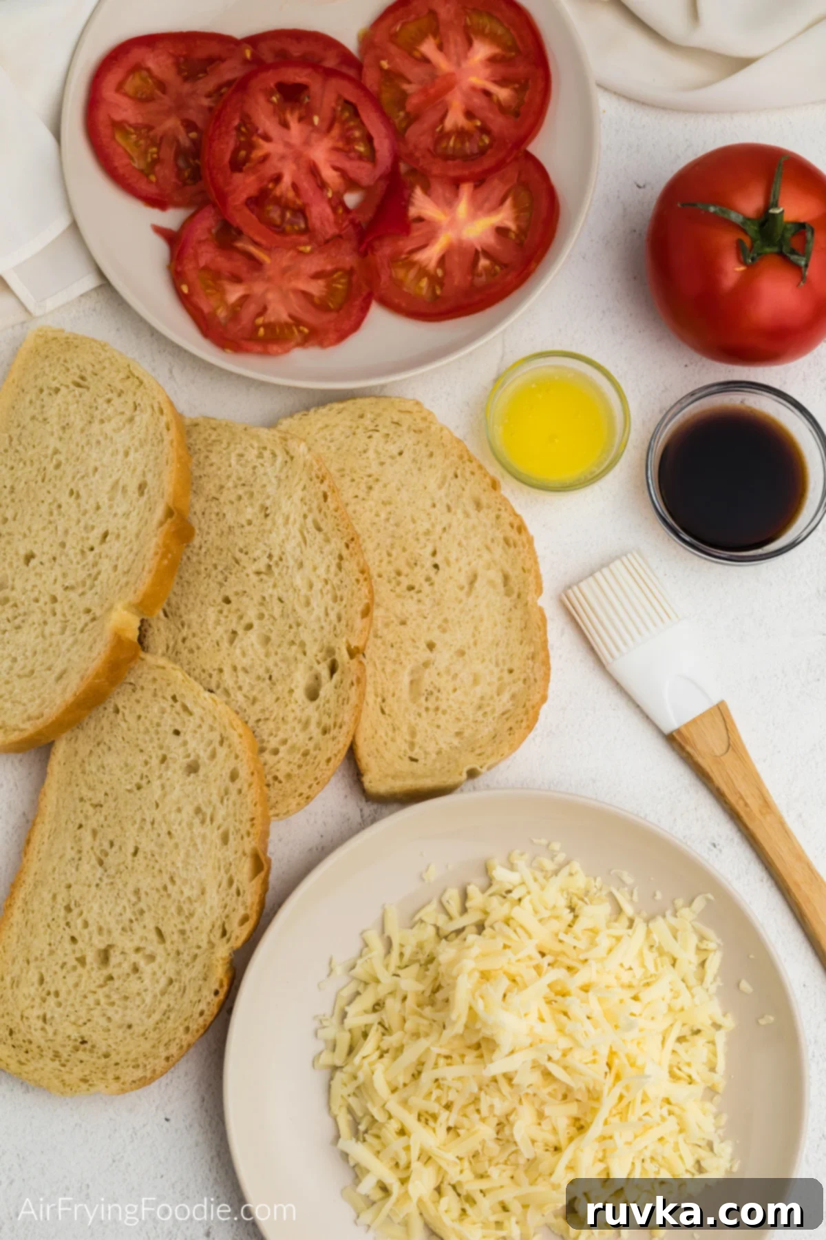 Crispy Air Fryer Tomato Cheese Melts 3 Sourdough bread, butter, balsamic vinegar, sliced tomatoes, and shredded cheese laid out as ingredients for the air fryer grilled tomato and cheese sandwich.