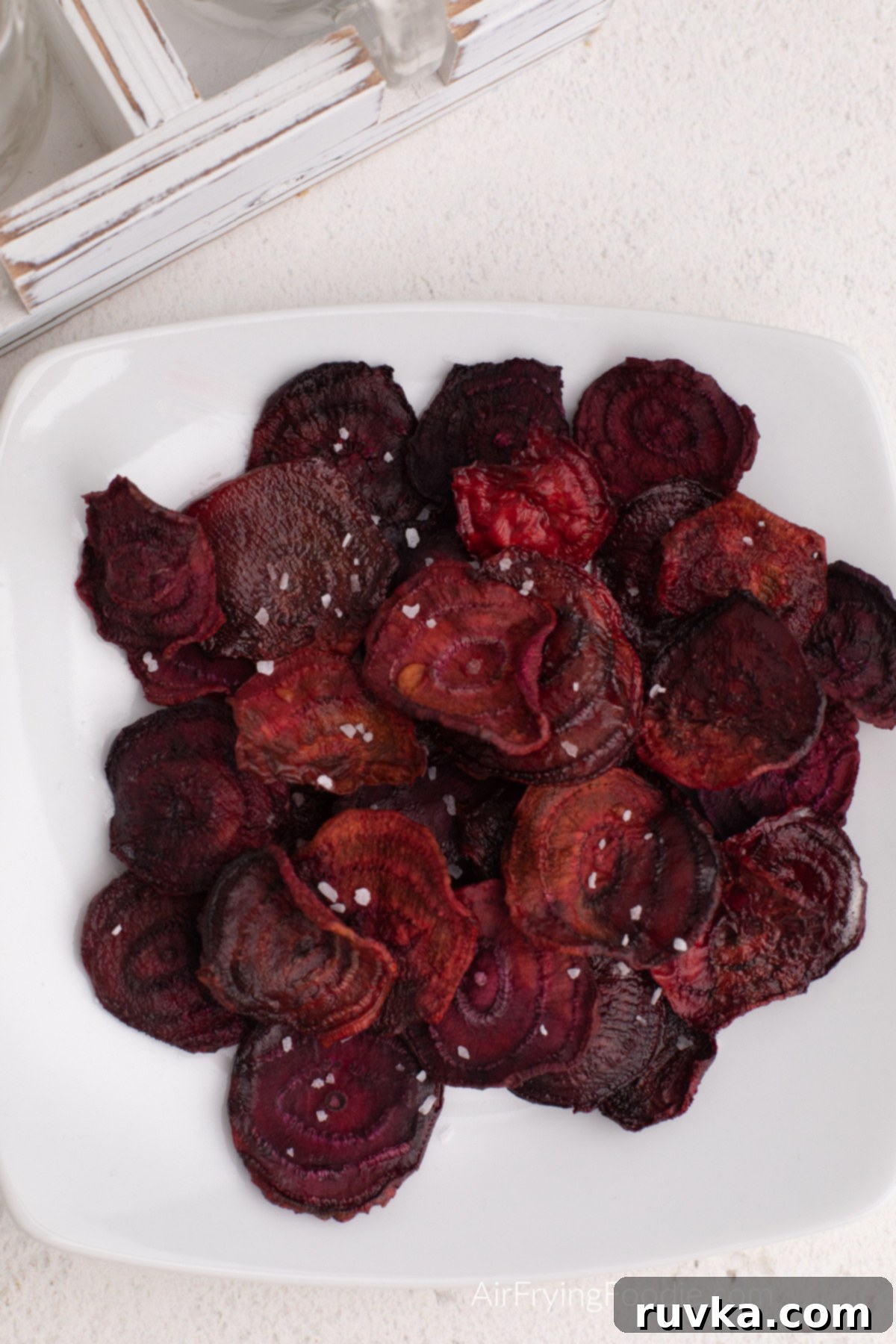 Crispy Air Fryer Beet Chips 8 Air fryer beet chips on a white plate, topped with kosher salt before serving.