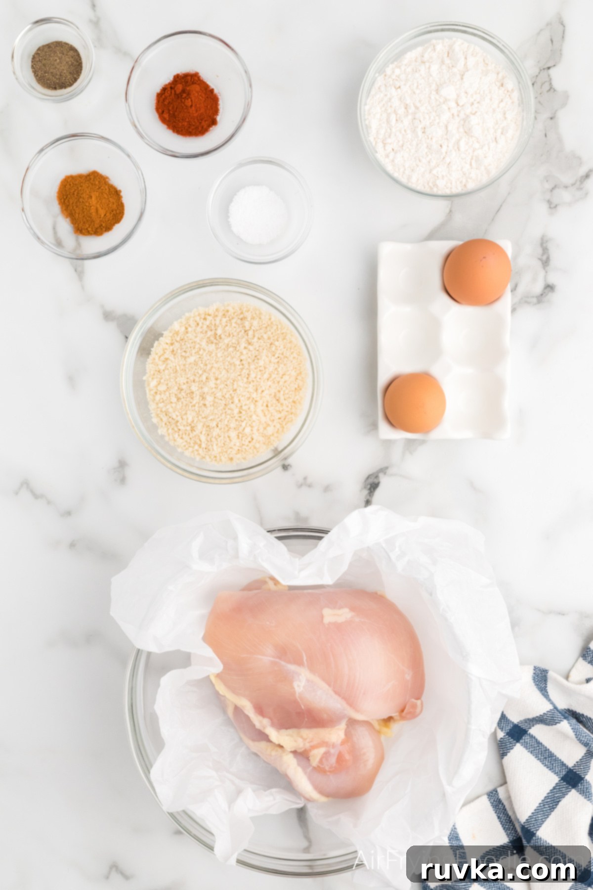 Air-Fried Chicken Poppers 3 Chicken, seasonings, eggs, flour, panko breadcrumbs, and olive oil cooking spray laid out, ready to make homemade air fryer popcorn chicken.