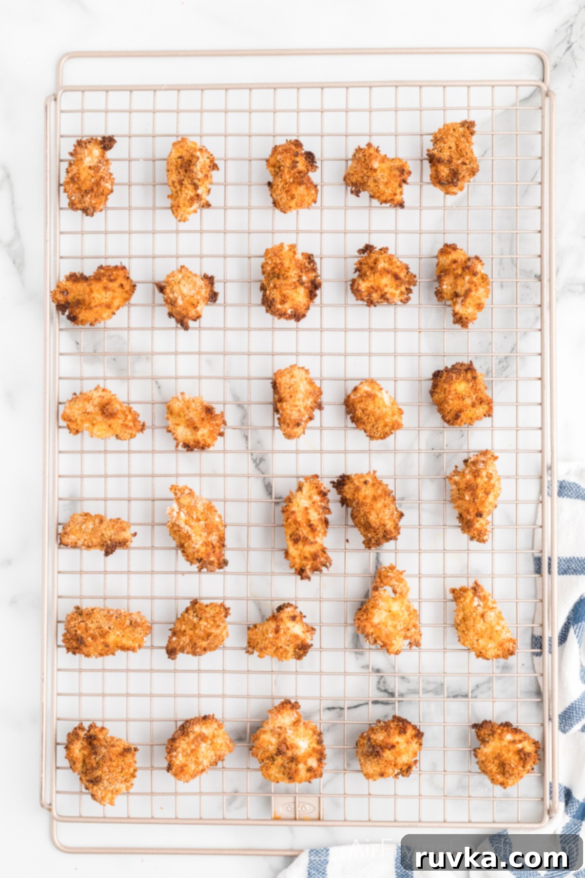 Air-Fried Chicken Poppers 7 Air fried popcorn chicken resting on a wired cooling rack to maintain its crispiness before being served.