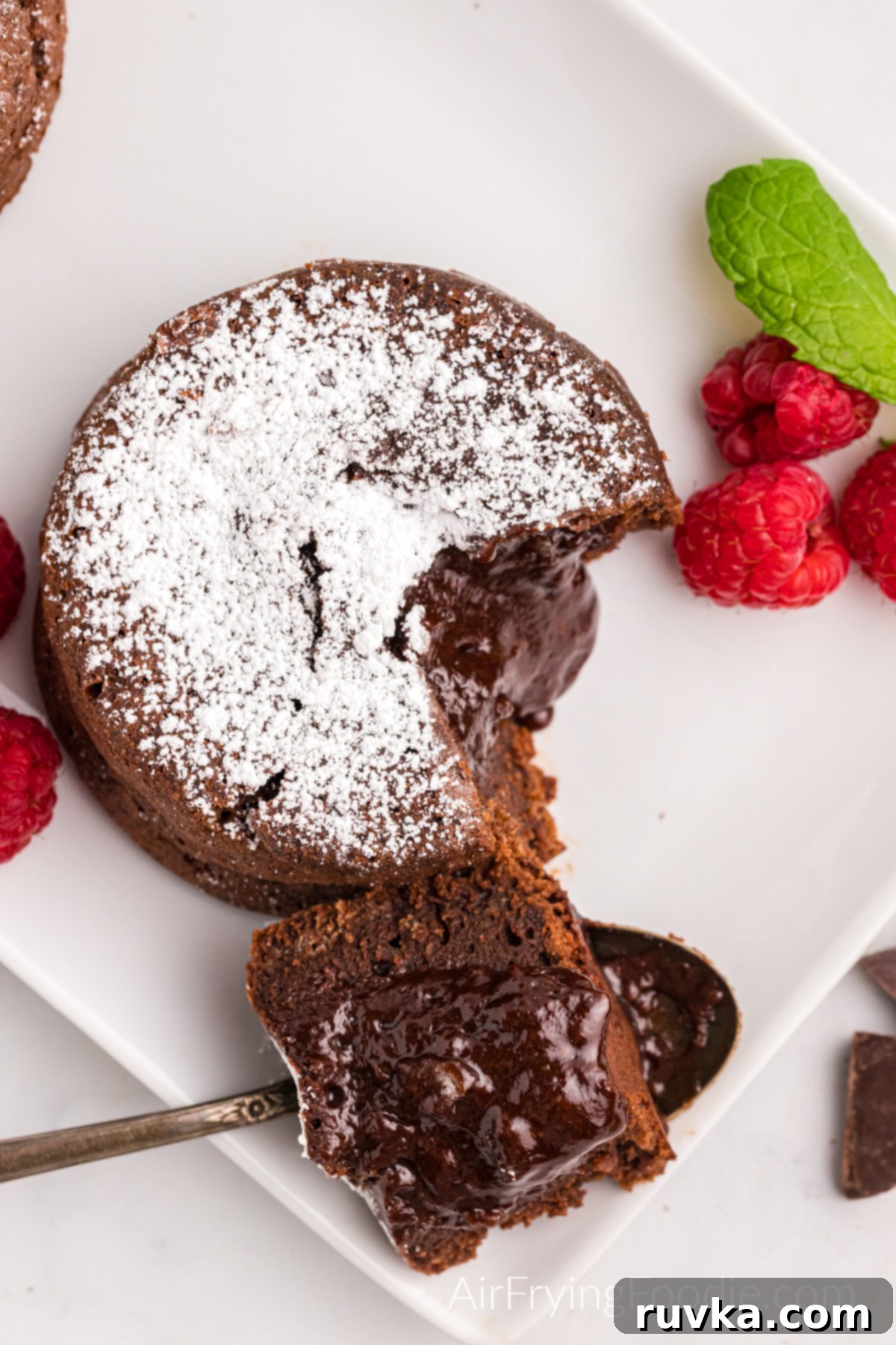 Easy Air Fryer Molten Chocolate Cakes 3 Bite shot removed from lava cakes made in the air fryer, and dusted with confectioner's sugar.