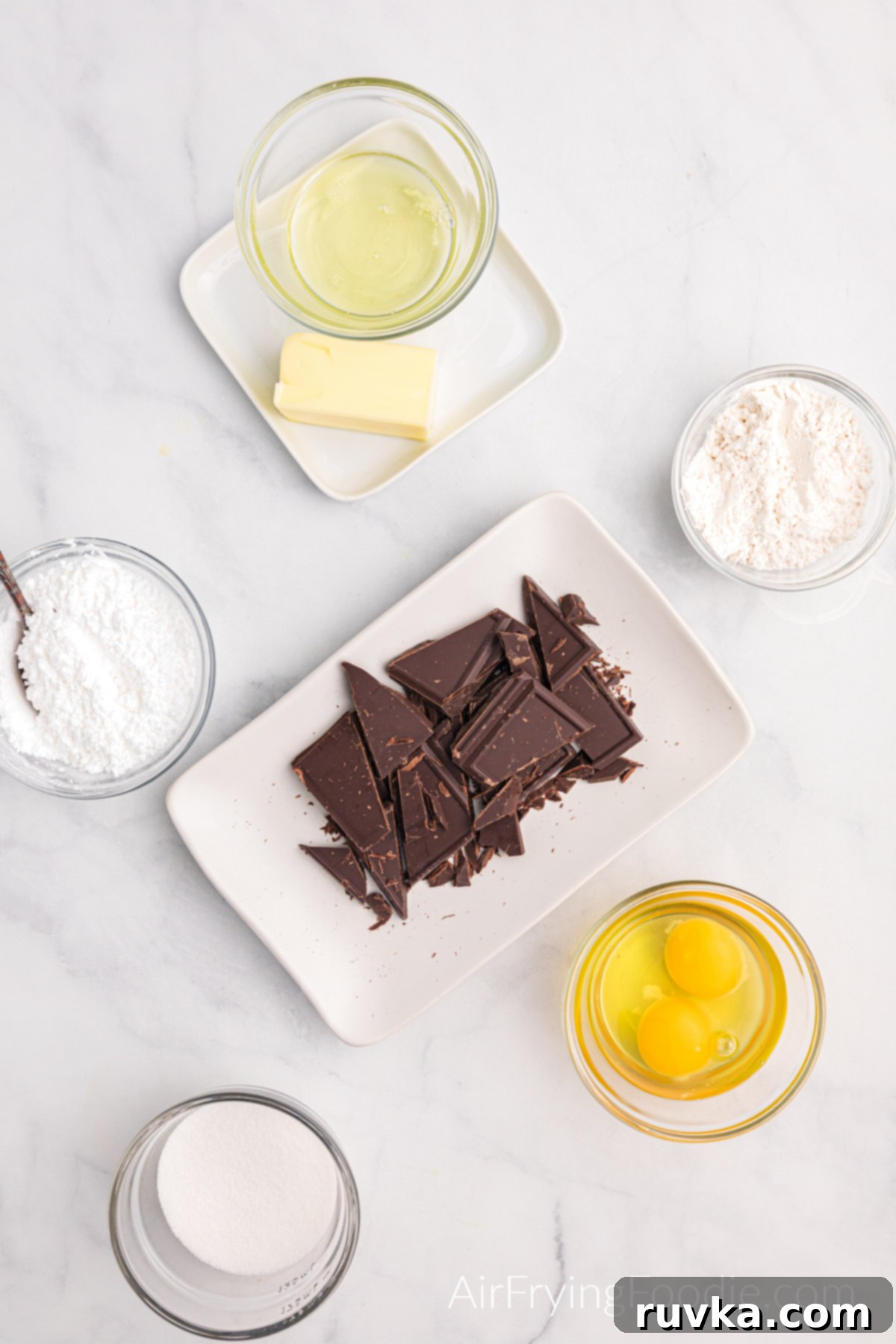 Easy Air Fryer Molten Chocolate Cakes 4 Ingredients needed to make air fryer lava cake measured in glass bowls on a marble table.