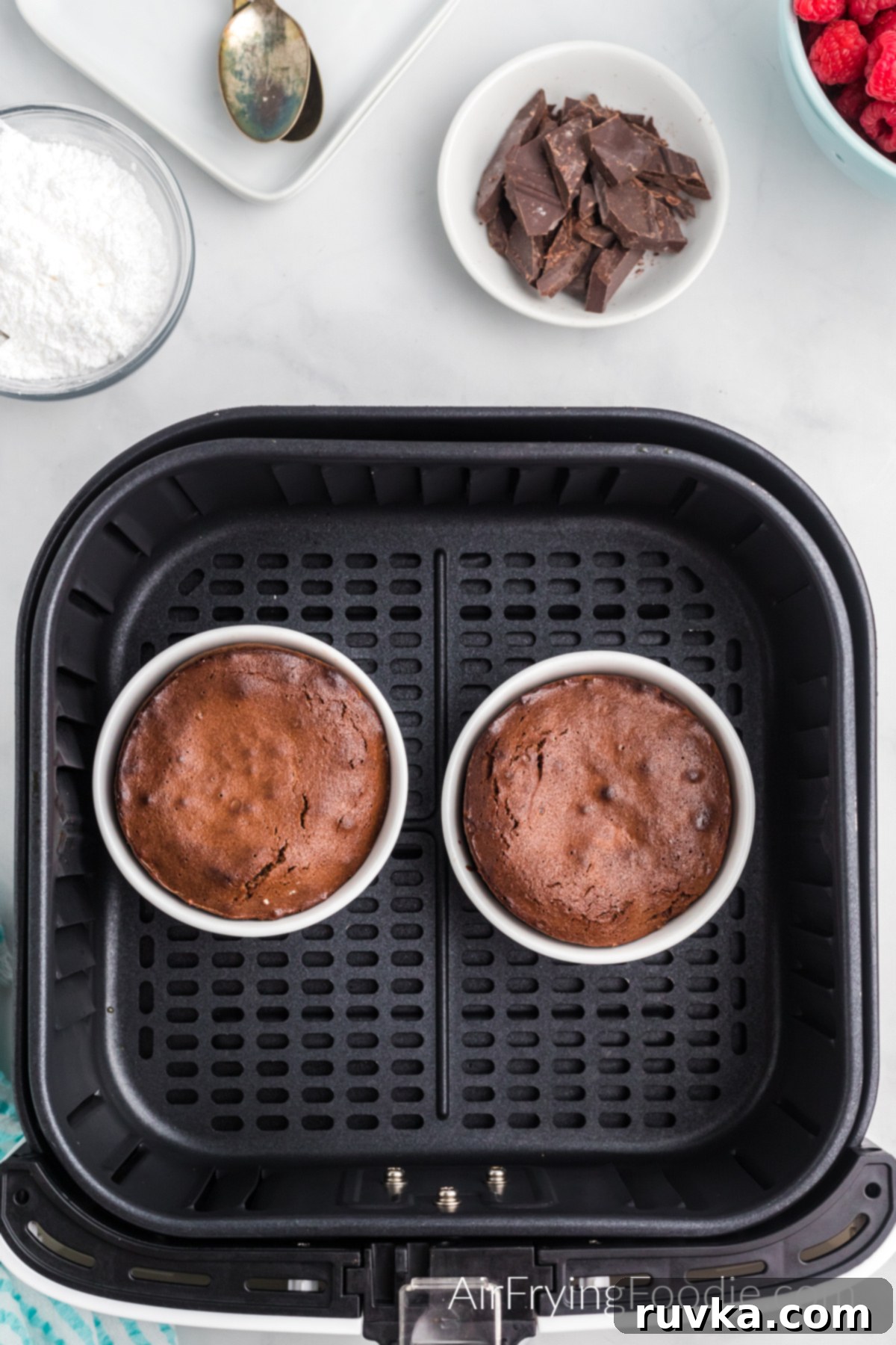 Easy Air Fryer Molten Chocolate Cakes 8 Lava cakes in ramekins in the basket of the air fryer.