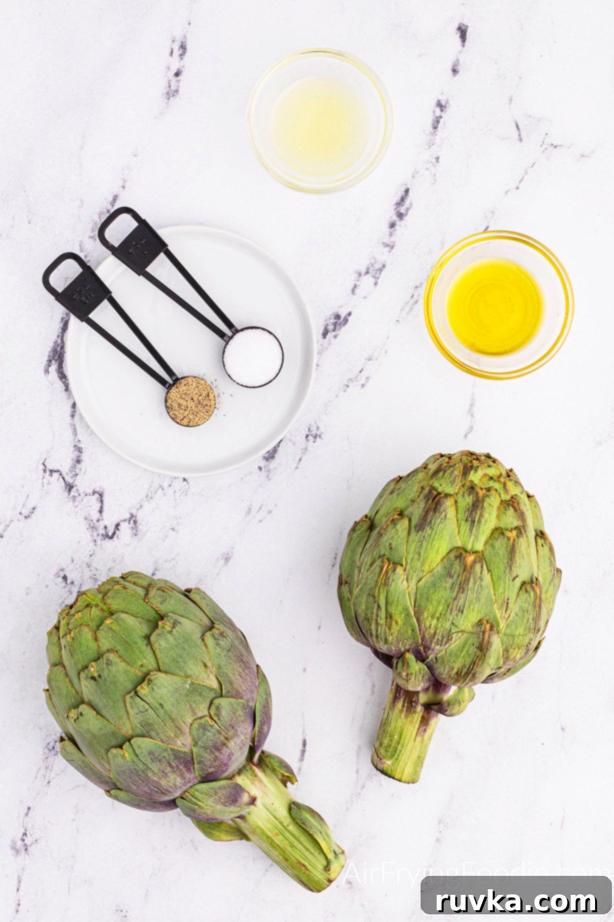 Air-Fried Artichoke Perfection 3 Ingredients needed for air fryer artichoke on a white table top.