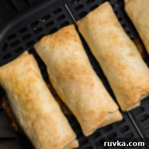 Perfectly Crispy Air Fried Frozen Burritos 7 Air fried burritos in the basket of the air fryer, cooked to a perfect crisp and golden-brown.