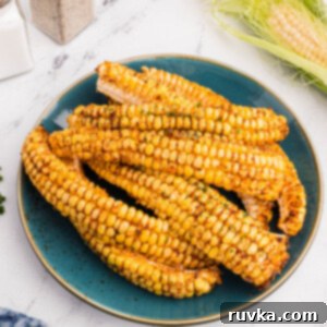 Crispy Air Fried Corn Ribs 11 Air fryer corn ribs served on a blue plate, garnished with fresh herbs.