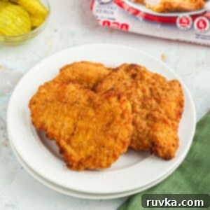 Quick Air Fryer Back to School Dinners 3 Golden crispy chicken breasts on a white plate in front of pickles and a red bag of chicken, indicating Aldi Red Bag Chicken made in an air fryer.