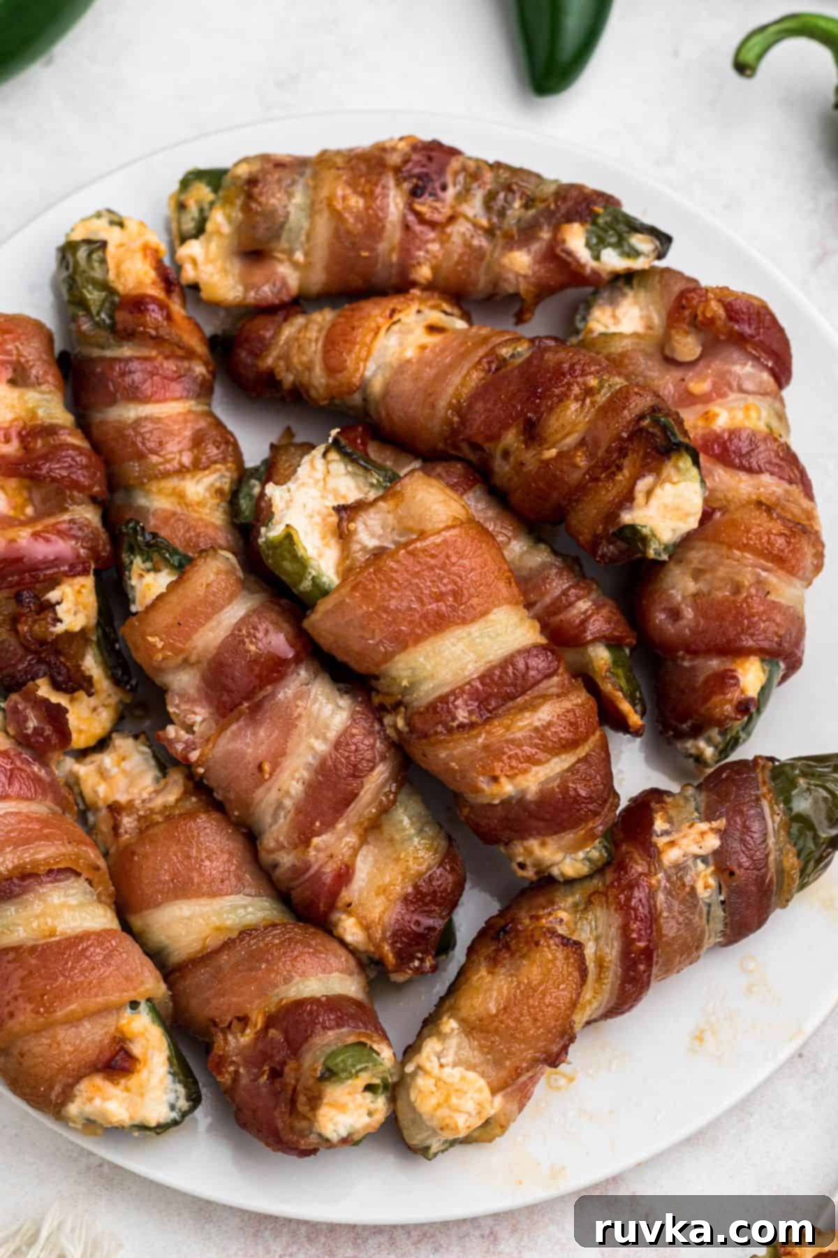 Crispy Air Fryer Jalapeño Poppers 2 Crispy cooked bacon wrapped jalapenos, filled with cheese mixture, on a white plate.
