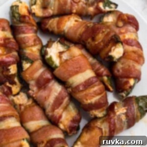 Crispy Air Fryer Jalapeño Poppers 11 Crispy cooked bacon wrapped jalapenos, filled with cheese mixture, on a white plate.