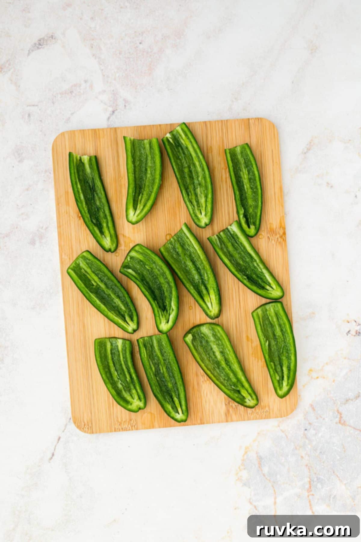 Crispy Air Fryer Jalapeño Poppers 4 Jalapenos sliced in half with seeds and insides removed, on a wooden cutting board.