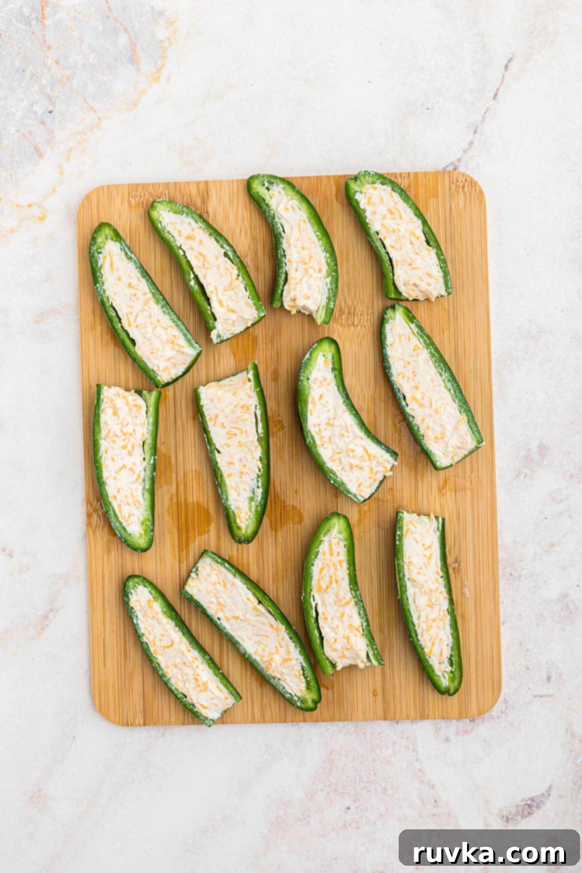 Crispy Air Fryer Jalapeño Poppers 6 Jalapenos, sliced in half, on a wooden cutting board and filled with cheese mixture.