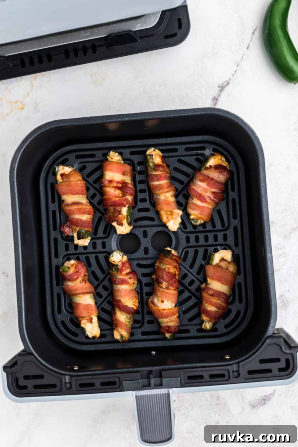 Crispy Air Fryer Jalapeño Poppers 9 Crispy cooked jalapeno poppers in the air fryer basket, in front of an air fryer.