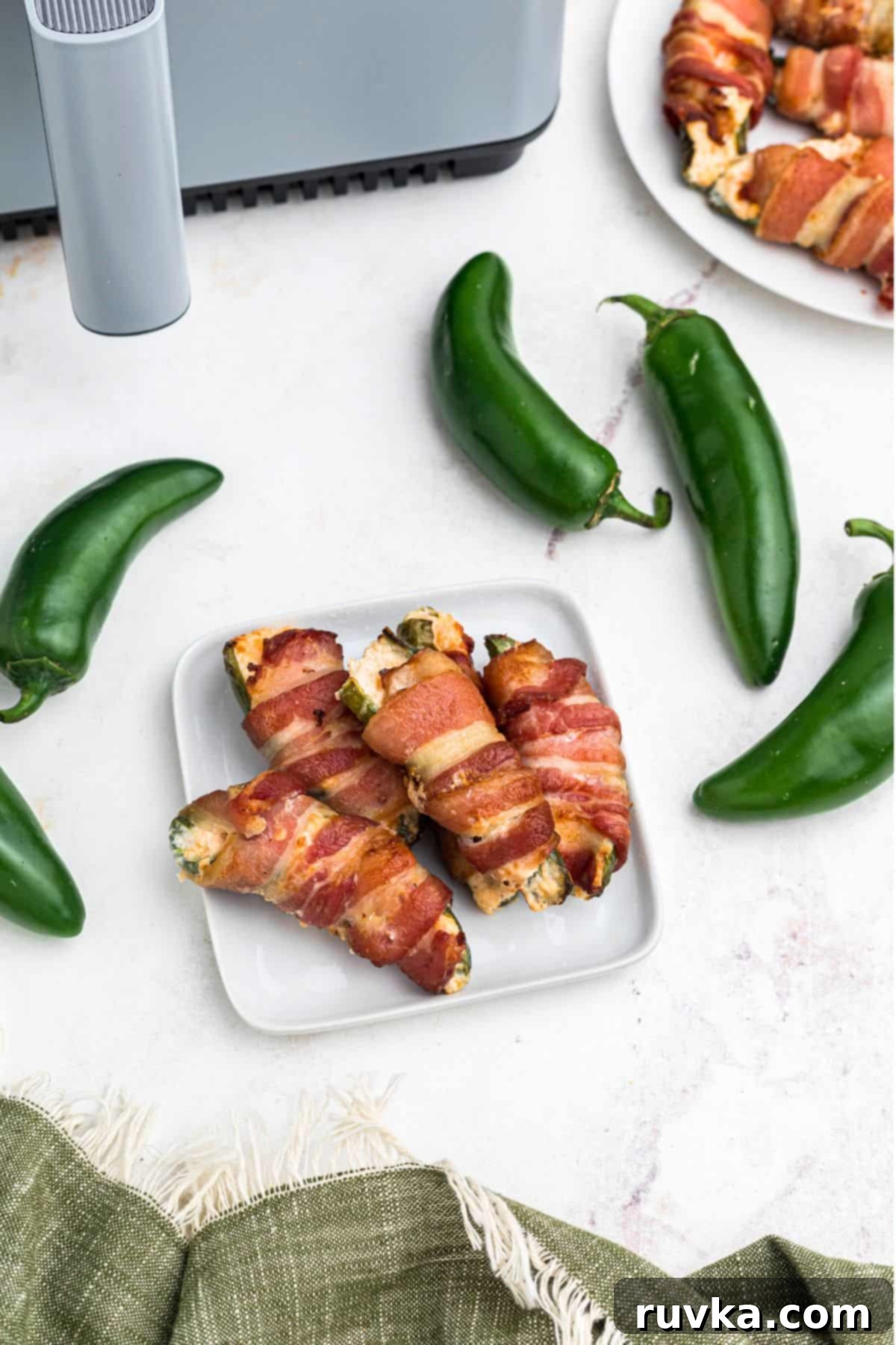 Crispy Air Fryer Jalapeño Poppers 10 Crispy bacon wrapped jalapeno poppers on a small white square plate.