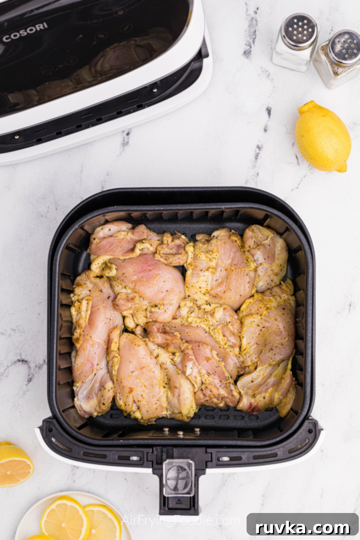 Crispy Air Fryer Lemon Pepper Chicken Thighs 6 Seasoned lemon pepper chicken thighs cooking in a single layer in the air fryer basket.