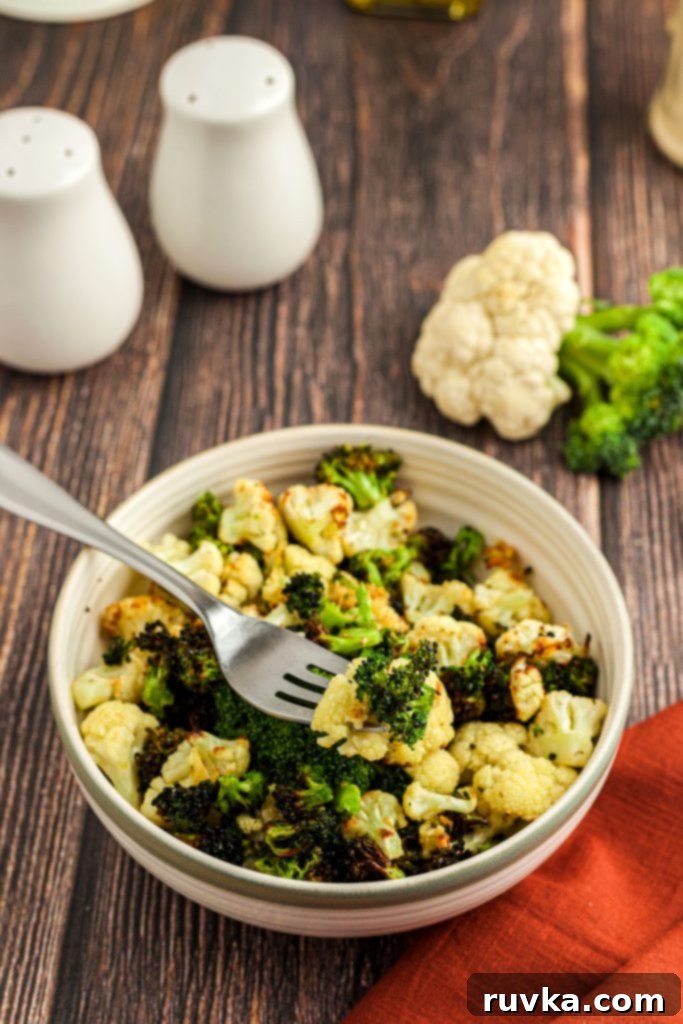 Crispy Air Fried Broccoli Cauliflower 2 Crispy broccoli and cauliflower in a tan bowl with a fork on a wooden table.