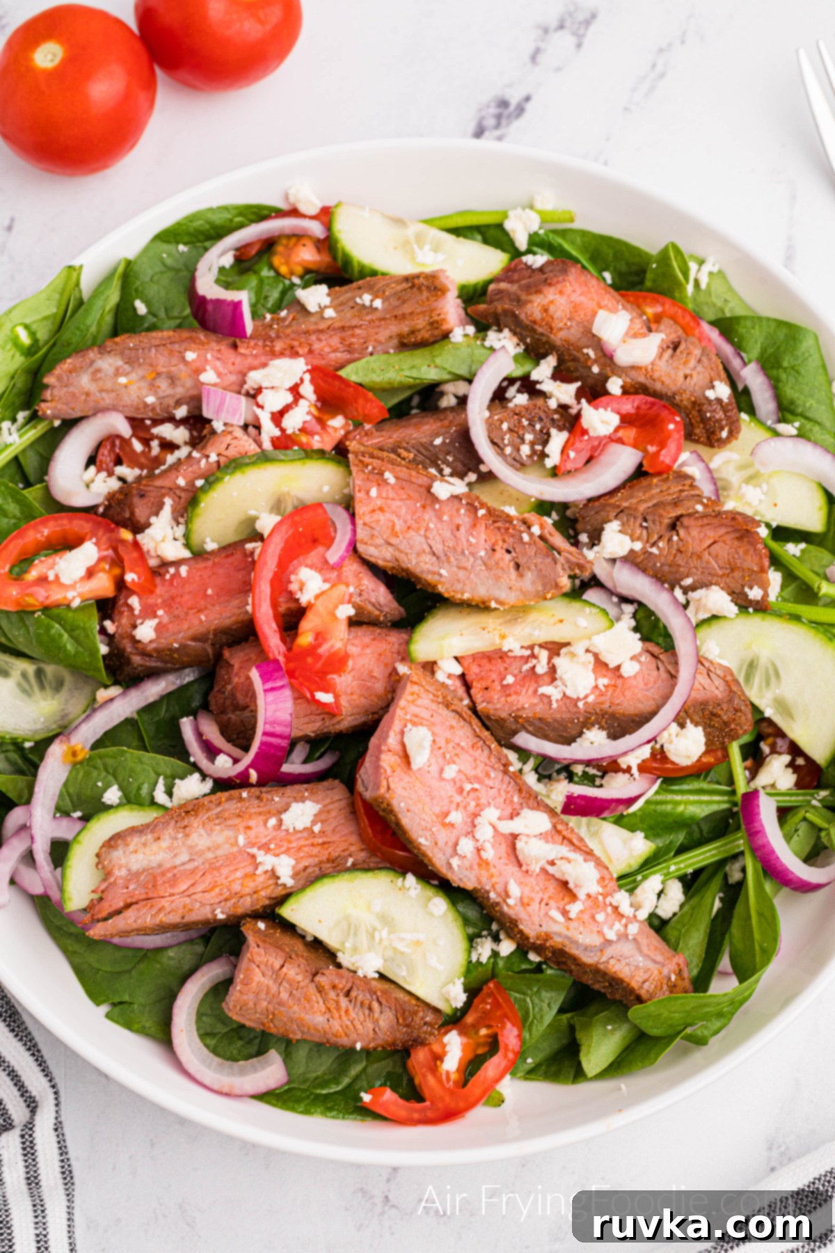 Perfect Air Fryer Flank Steak 11 Air fried flank steak on a platter with salad fixings for a steak salad.