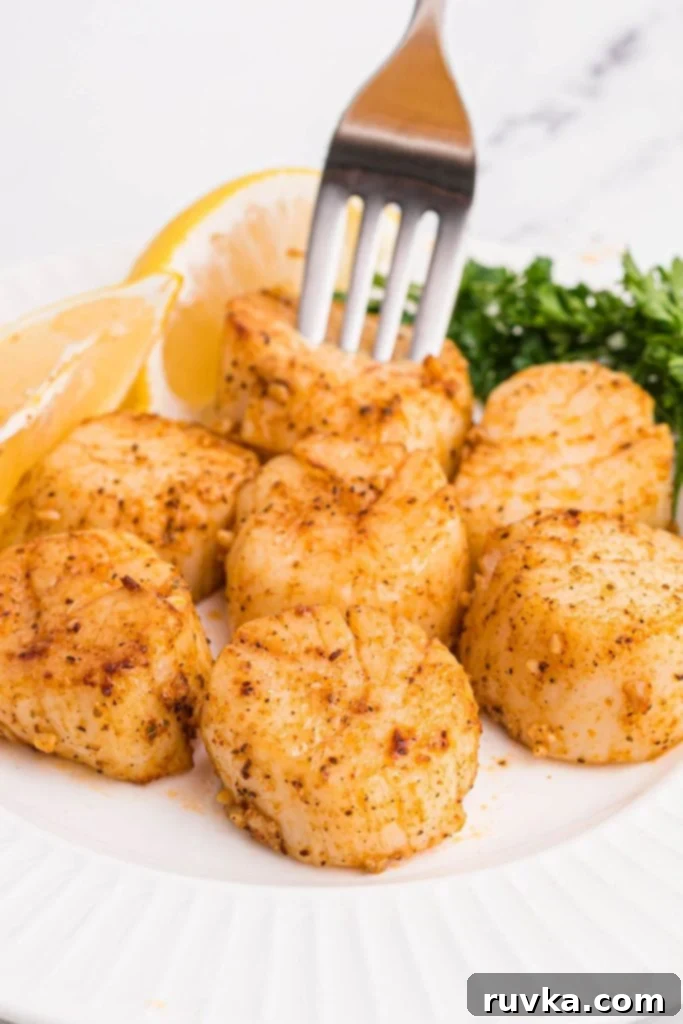 Crispy Air Fryer Scallops 2 Golden juicy scallops on a white plate with lemon wedges