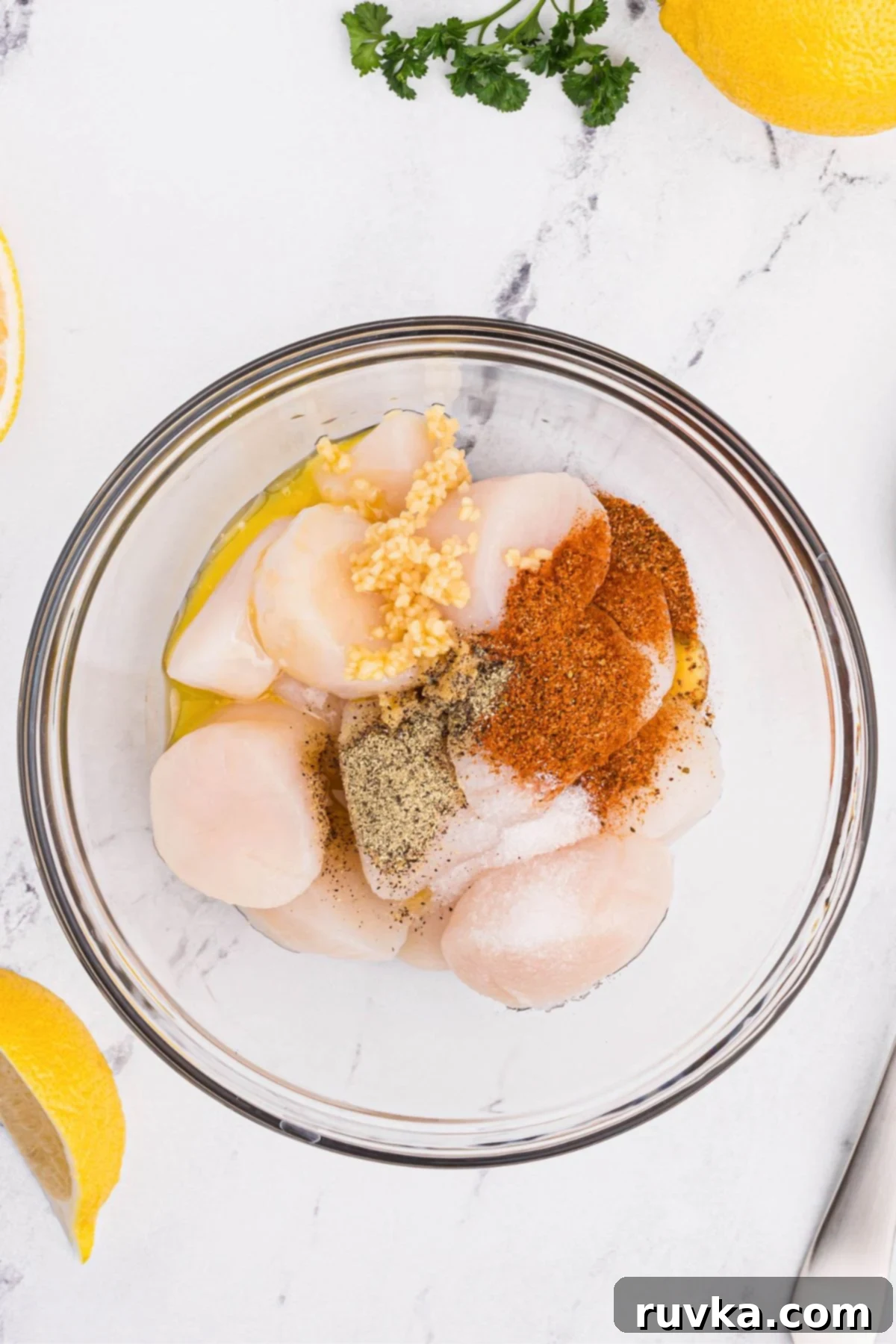 Crispy Air Fryer Scallops 4 Seasonings mixed with uncooked sea scallops in a clear glass bowl.