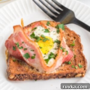 Easy Air Fryer Breakfast Sandwich 10 Fully cooked air fryer toast with bacon and egg served on a round white plate with a fork.