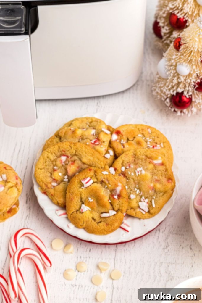Holiday Air Fryer White Chocolate Chip Peppermint Cookies 2 Golden cookies filled with white chips and crushed peppermints on a white plat