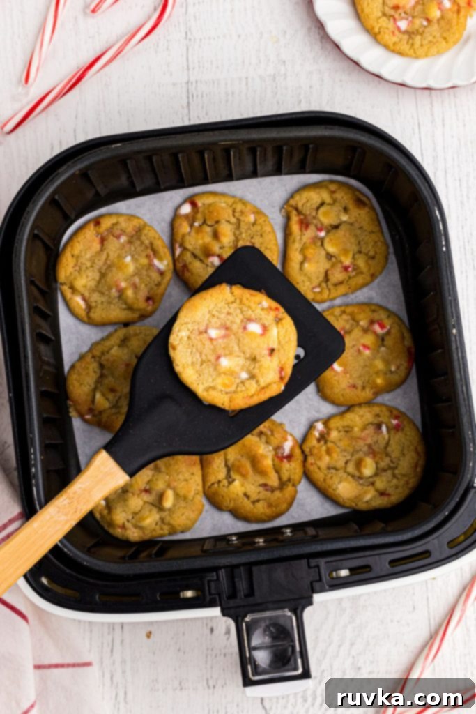 Holiday Air Fryer White Chocolate Chip Peppermint Cookies 11 Golden cookie on a black spatula being lifted out of an air fryer basket