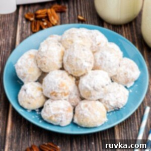 Easy Air Fryer Snowball Cookies 13 White powdered coated snowball cookies stacked on a blue plate