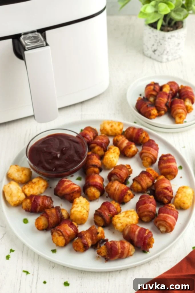 Crispy Air Fryer Bacon-Wrapped Tater Tots 2 Golden bacon wrapped tater tots on a large white plate with BBQ sauce