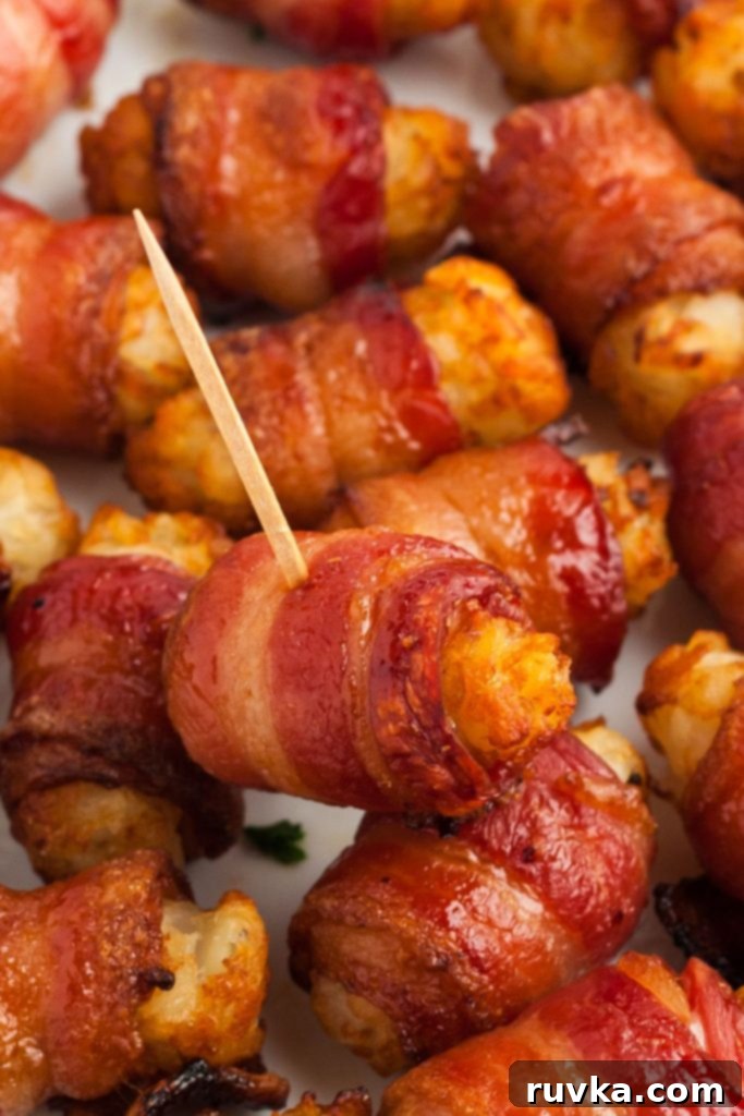 Crispy Air Fryer Bacon-Wrapped Tater Tots 9 Juicy crispy bacon wrapped tater tots stacked on a white plate