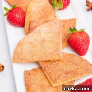 Crispy Air Fryer Cinnamon Sugar Tortilla Chips 12 Cinnamon and sugar coated tortilla chips on a white plate with fresh strawberries