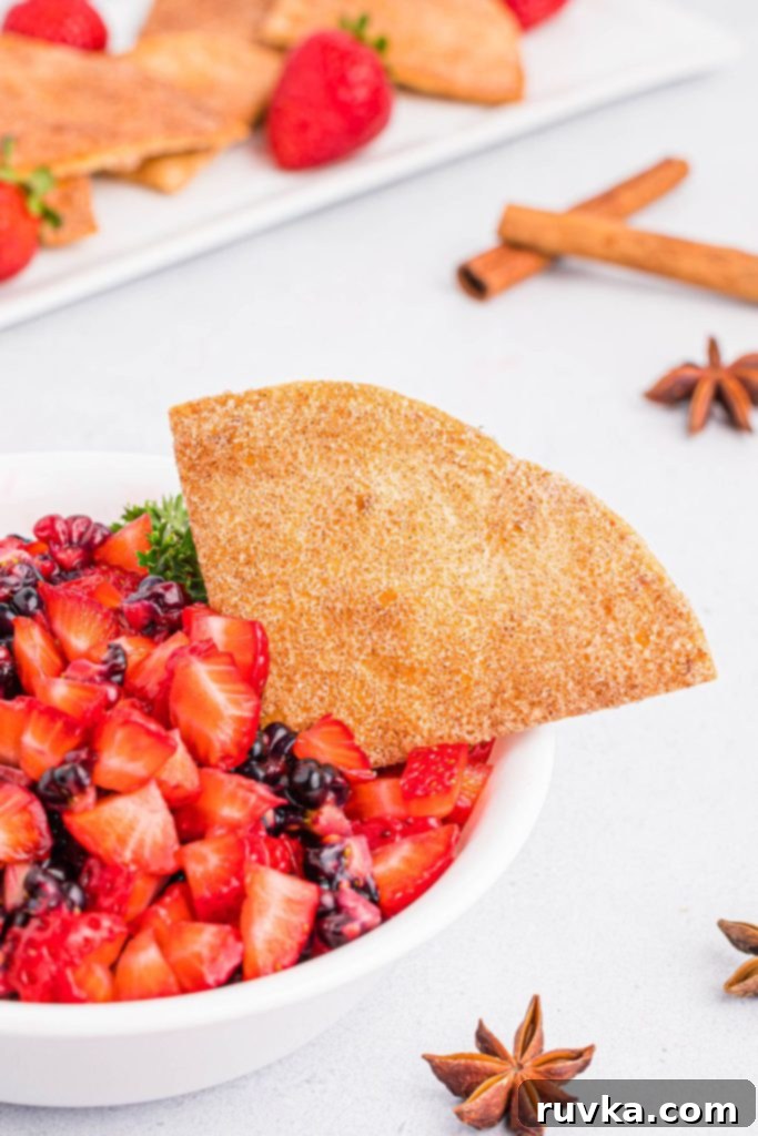 Crispy Air Fryer Cinnamon Sugar Tortilla Chips 3 Cinnamon coated tortilla chips in a bowl filled with chopped fruits