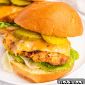 Crispy Homemade Air Fryer Chick-fil-A 14 Air fryer copycat chick fil a sandwich dressed with pickles, cheese, lettuce, and sauce and served on a round white plate.
