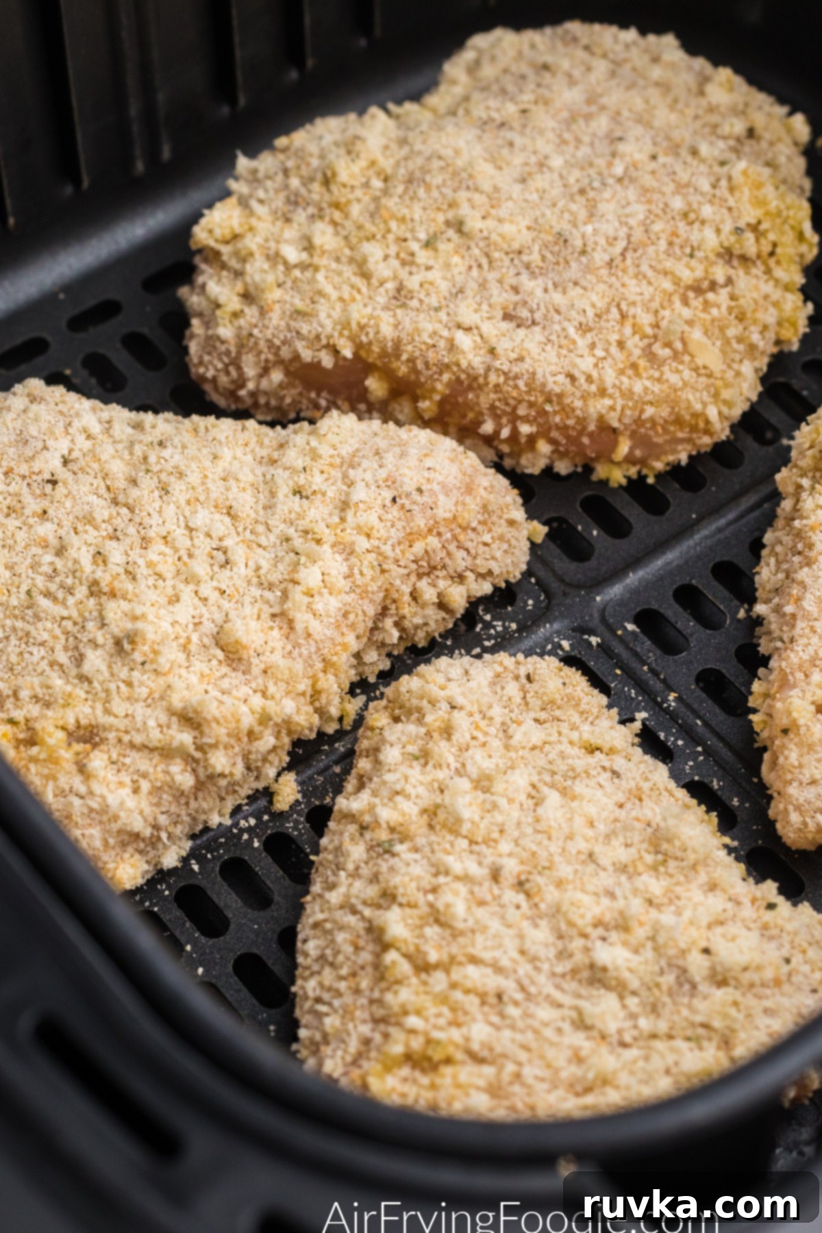 Crispy Air Fryer Chicken Parmesan 4 Coated parmesan chicken in the basket of the air fryer.