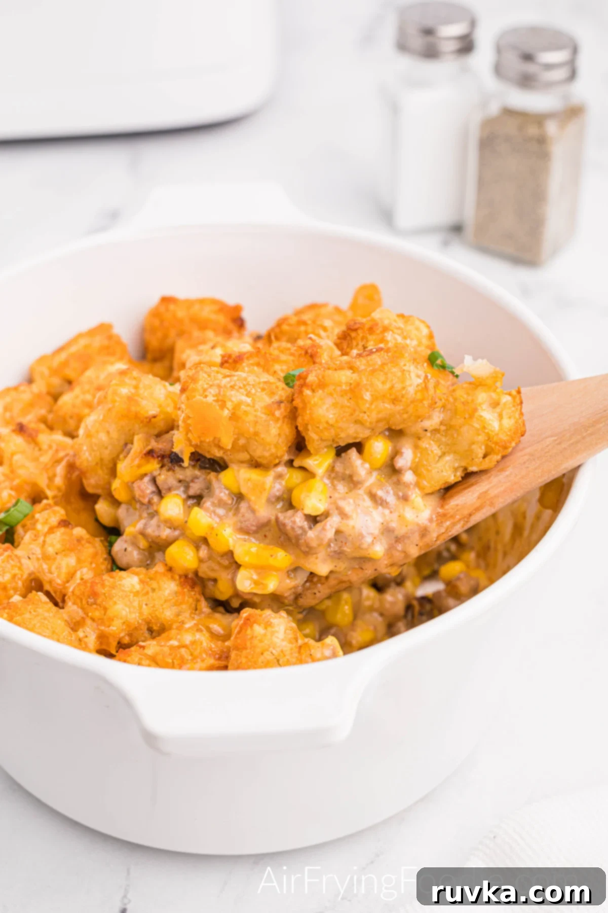 Hearty Air Fryer Cowboy Casserole 2 Fully cooked air fryer cowboy casserole in a white bowl with a spoonful of casserole ready to serve and a salt and pepper shaker.