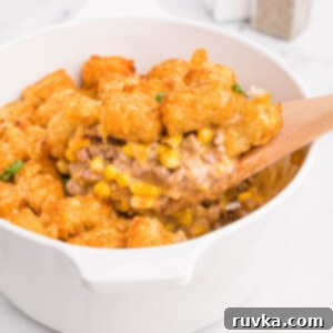 Hearty Air Fryer Cowboy Casserole 13 Air fryer cowboy casserole fully cooked with a wooden spoon removing a serving.