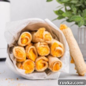 Crispy Cheesy Air Fryer Roll Ups 11 Grilled cheese roll ups cooked in the air fryer and served in a tin container lying on its side.