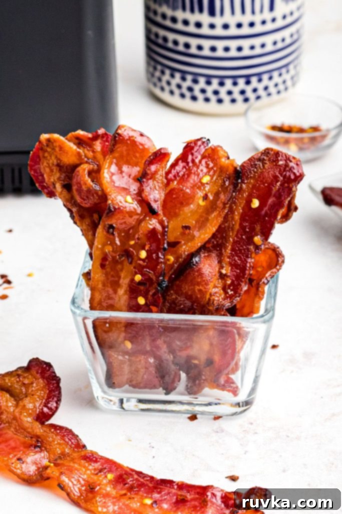 Crispy Sweet Air Fryer Bacon 2 Golden crispy candy bacon in a glass dish in front of the air fryer.