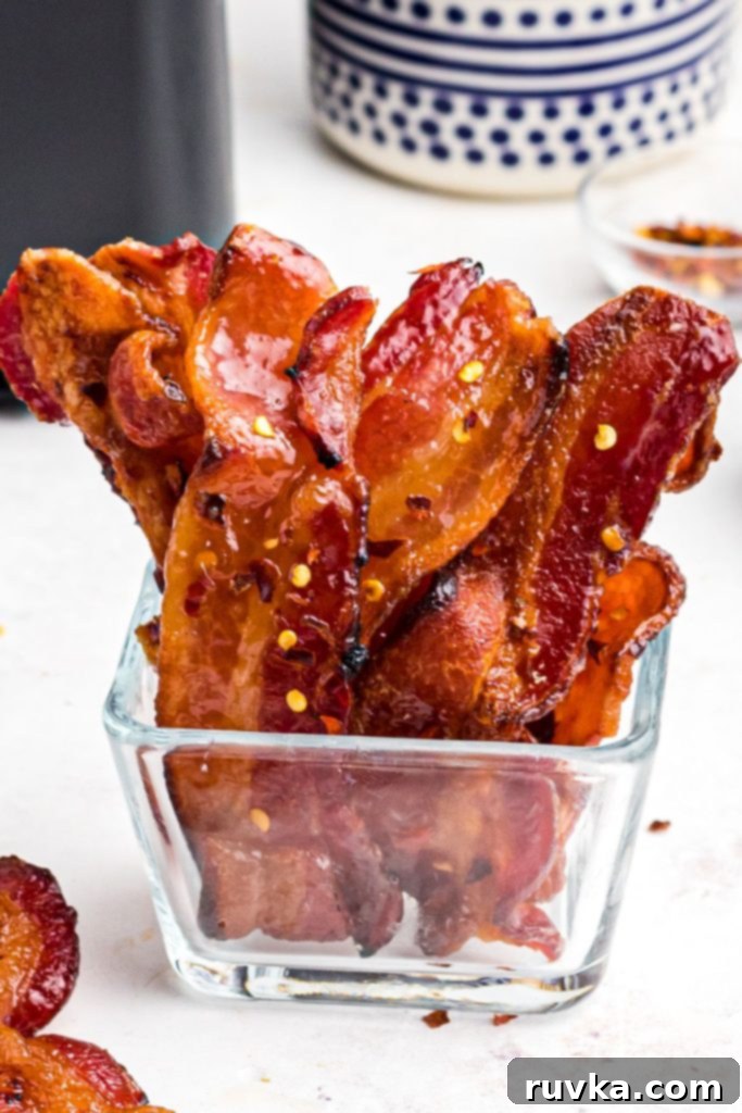 Crispy Sweet Air Fryer Bacon 9 Juicy bacon in a glass jar seasoned with red pepper flakes.