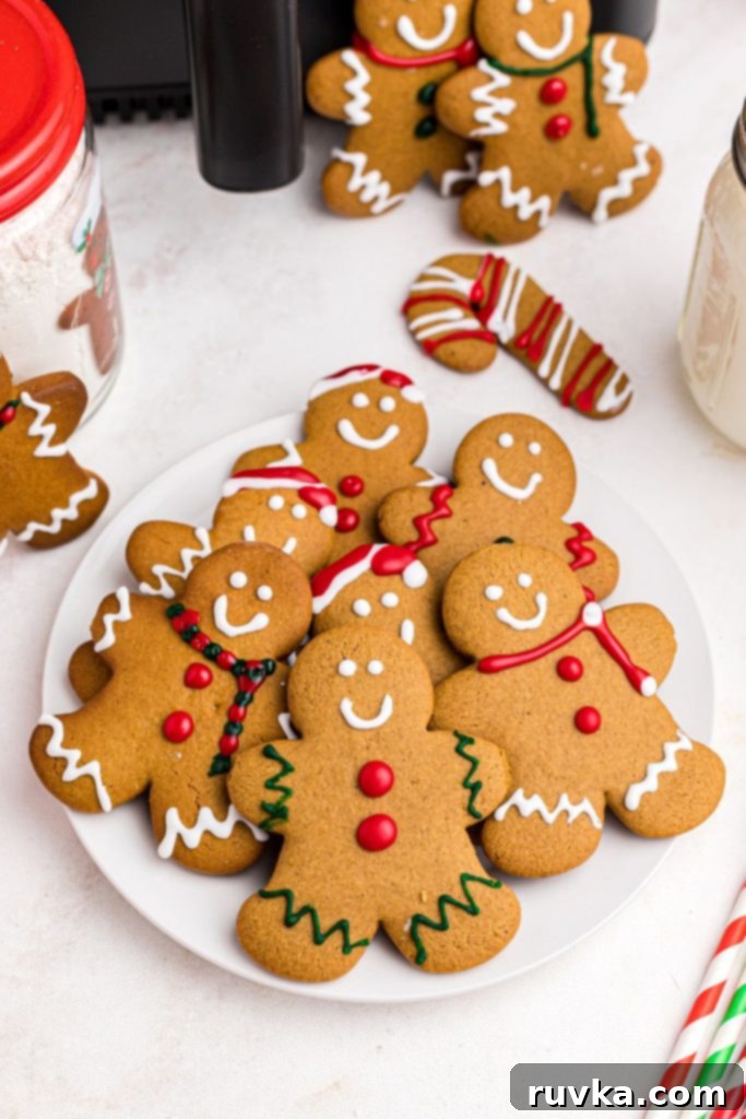 Quick and Easy Air Fryer Gingerbread Delights 2 Golden gingerbread men on a white plate in front of an air fryer, perfectly baked and ready to be decorated.