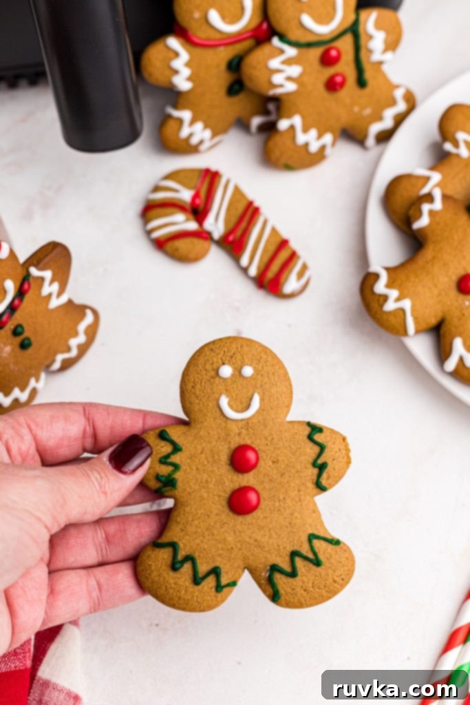 Quick and Easy Air Fryer Gingerbread Delights 3 A hand gently holding a golden gingerbread man cookie decorated with white frosting, showcasing its inviting texture.