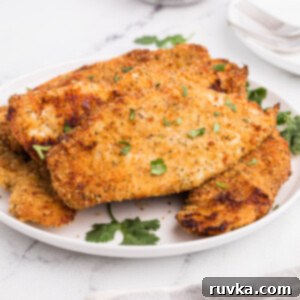 Perfectly Golden Air Fryer Chicken Cutlets 9 Fully cooked in the air fryer, chicken cutlets served on a white plate with parsley.