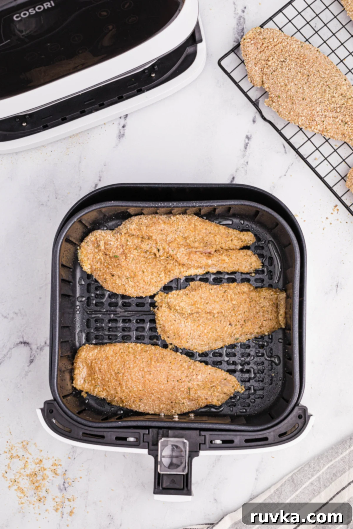 Perfectly Golden Air Fryer Chicken Cutlets 5 chicken cutlets in the air fryer basket, ready to be air fried.