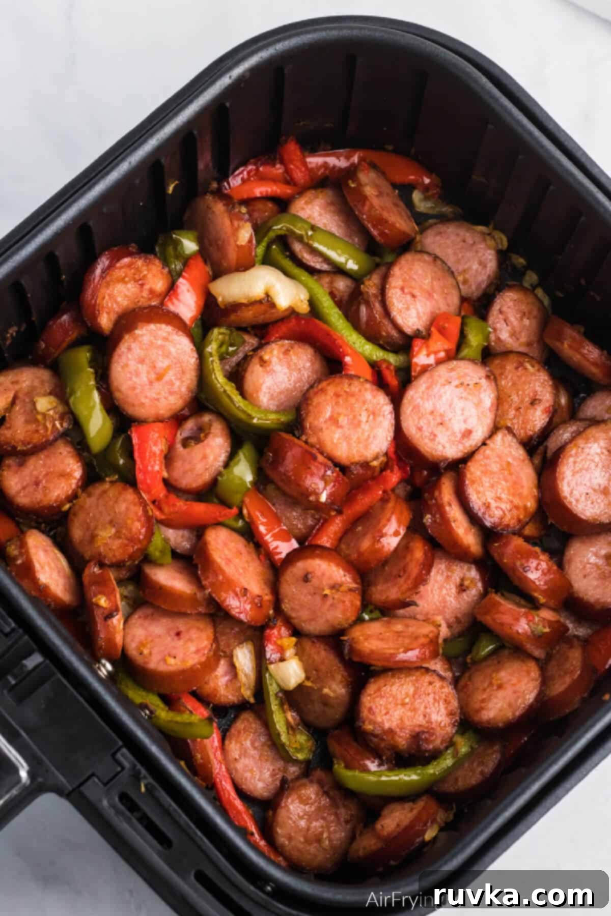 Crispy Air Fryer Sausage and Peppers 2 Seasoned sausage and peppers in air fryer basket, ready to serve.