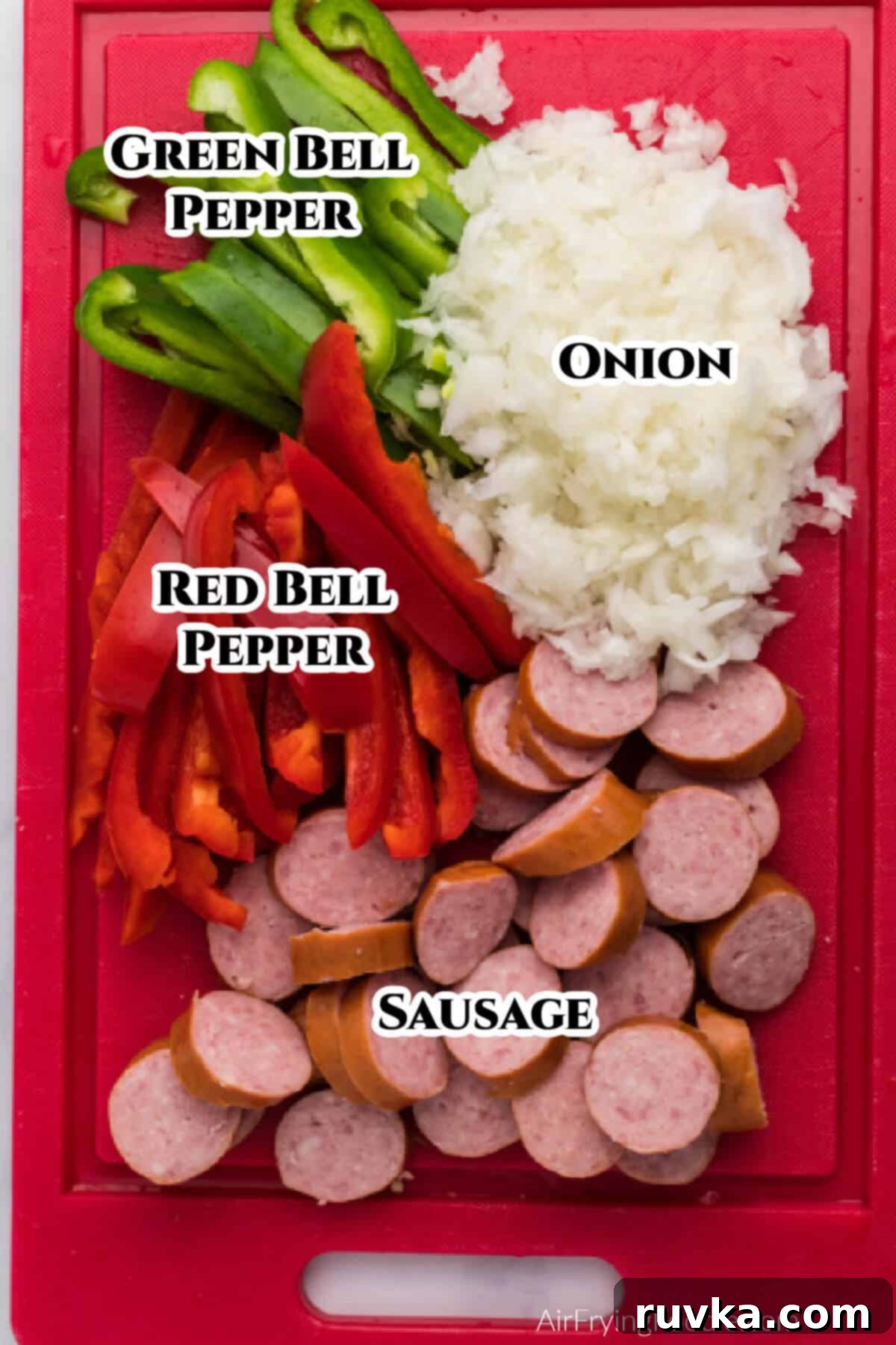 Crispy Air Fryer Sausage and Peppers 3 Red cutting board with sliced bell peppers, sausage, and diced onions.
