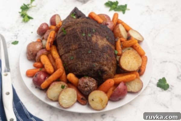 Crispy Air Fryer Top Round 2 Air Fryer top round roast, cooked and served on a white plate with potatoes and carrots.