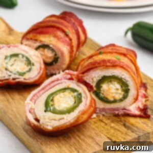 Crispy Air Fryer Chicken Jalapeno Poppers 13 Crispy bacon wrapped around chicken, wrapped around jalapeno poppers on a wooden cutting board.