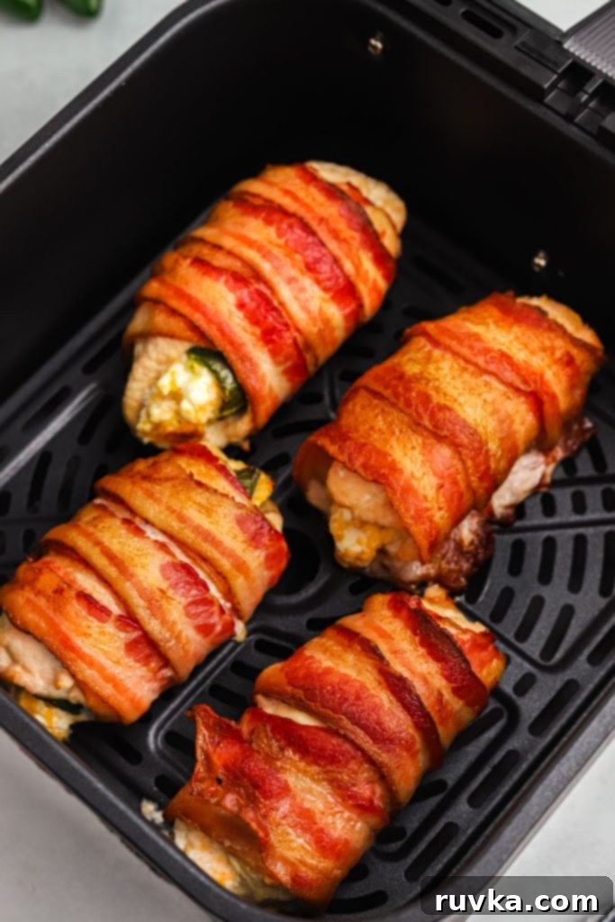 Crispy Air Fryer Chicken Jalapeno Poppers 10 Crispy golden bacon wrapped around chicken breasts stuffed with jalapenos and cheese, garnished with fresh herbs.