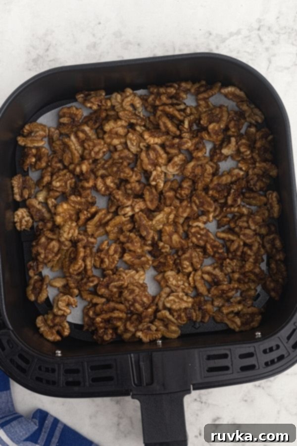 Crispy Sweet Air Fryer Walnuts 5 Walnuts in the air fryer basket, after being heated with the melted butter and sugars with seasonings.