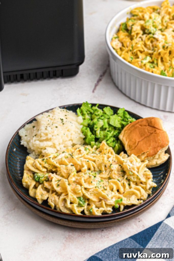 Crispy Air Fryer Chicken Casserole 2 Cheesy creamy chicken and egg noodles with veggies on a blue plate, garnished with fresh herbs.